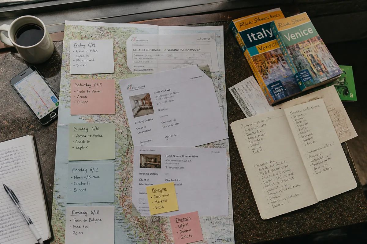 Overhead documentary travel planning scene with folded maps, hotel confirmations, day cards, and a smartphone route map